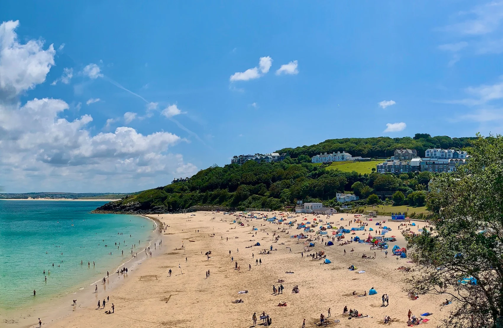 Families on the golden sand at Porthminster Beach in St Ives, Cornwall, with calm turquoise water in the bay