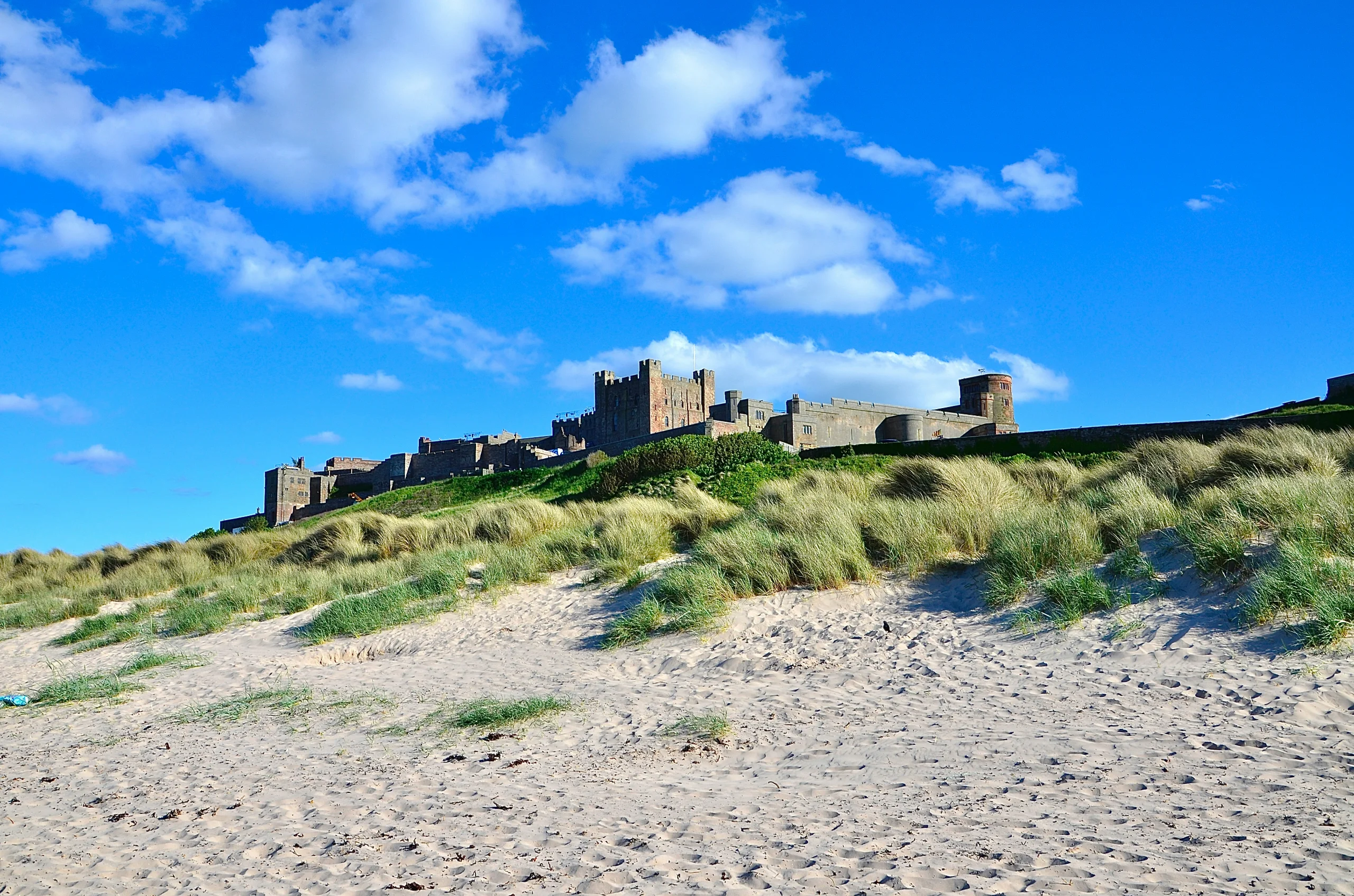 Bamburgh Castle on its rocky outcrop above the dunes and wide sandy beach on the Northumberland coast