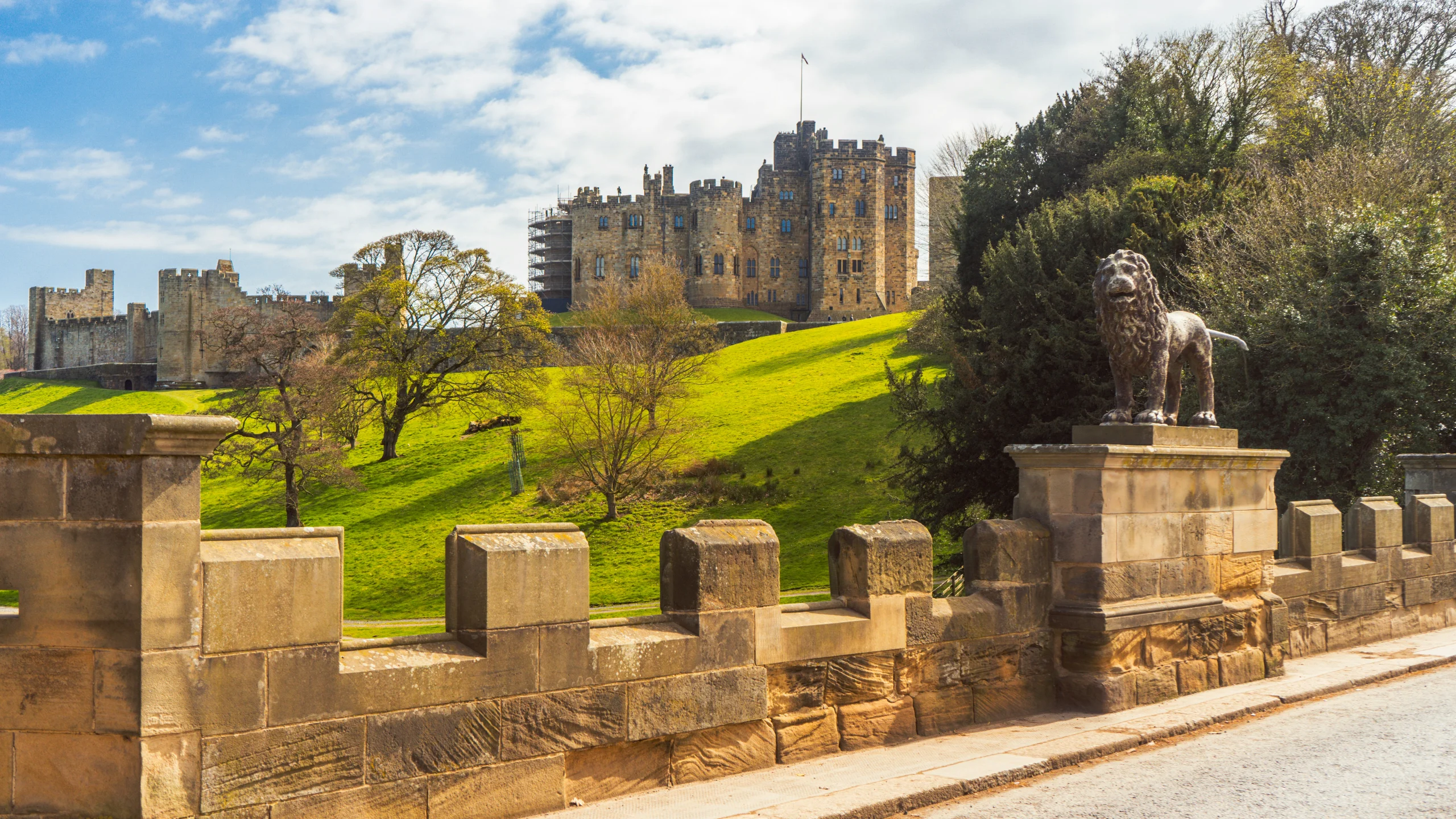 Alnwick Castle in Northumberland seen across the grass from the river side