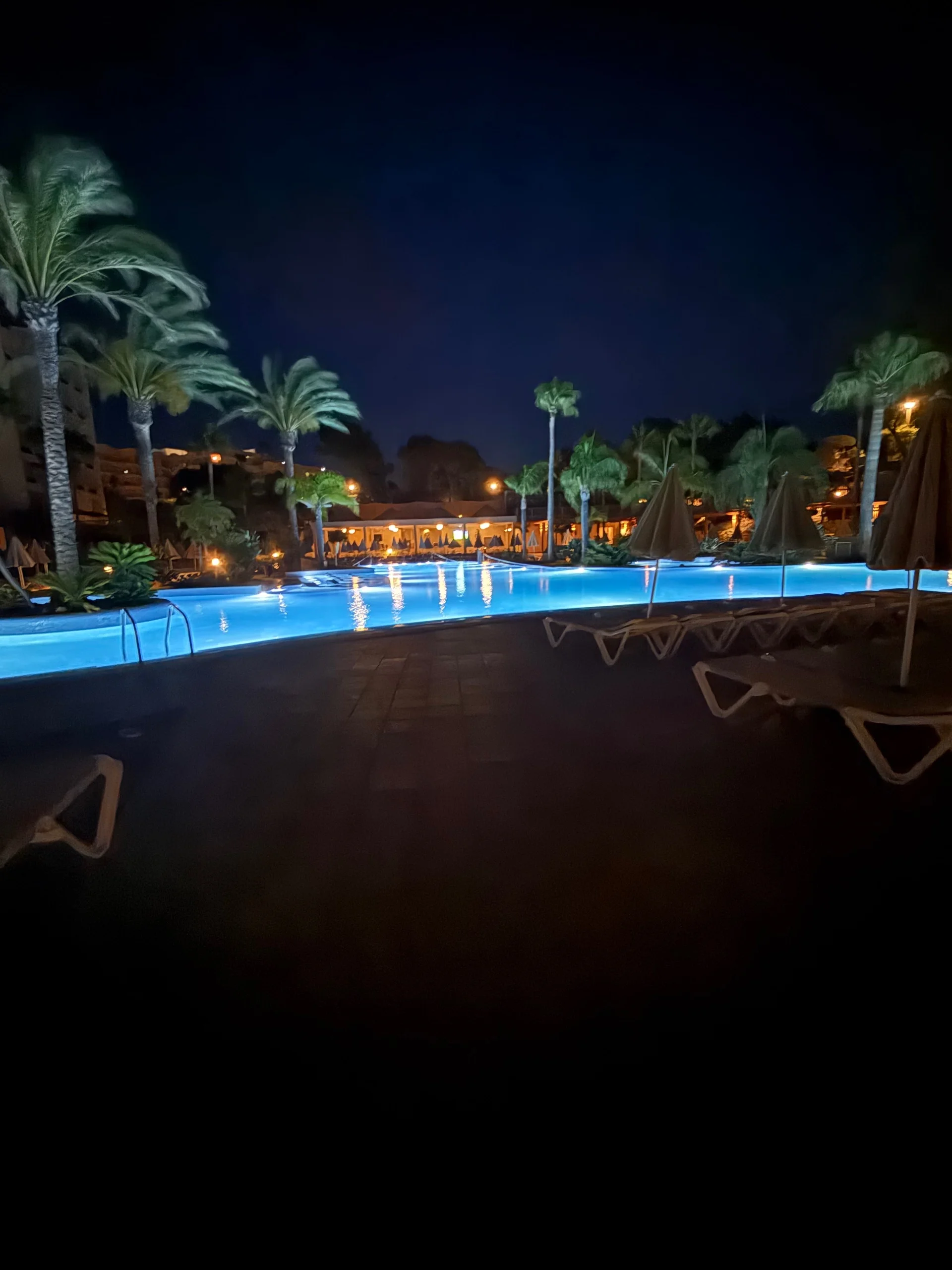 The main pool at 3HB Guaraná lit up after dark, with the resort buildings behind it