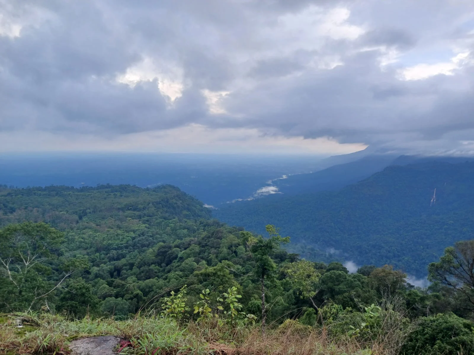 View over forested hills and low cloud from the top of the climb above Nong Luong